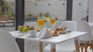 Ein Esstisch mit verschiedenen Früchten, Gebäck und einem Glas Orangensaft.