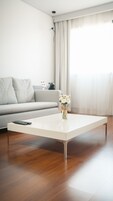A modern living room with a white coffee table, a grey sofa, and a vase with white flowers.
