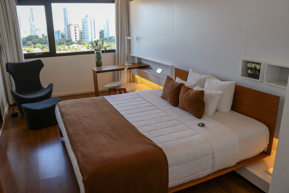 Une chambre d’hôtel avec un lit, un bureau, une chaise et une vue sur la ville.