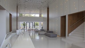 Ein modernes Interieur mit einer langen, weißen Rezeption, einer Sitzecke und einer Treppe.