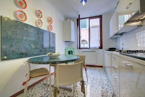 A kitchen with a round table, chairs, and a window. - REMIGIO Marco-canal (Venice)