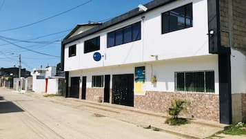 Un edificio de dos pisos con techo plano, varias ventanas y una señal visible.