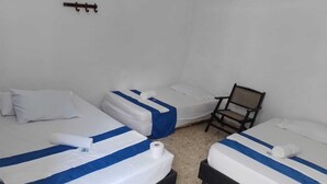Habitación con tres camas, cada una con ropa de cama a rayas blancas y azules, una silla y un gancho en la pared.