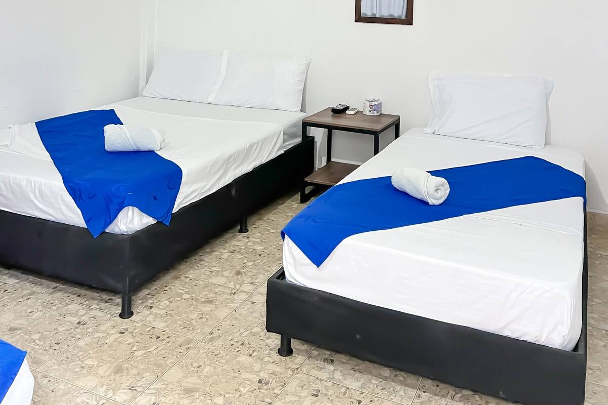 A hotel room with two beds, a ceiling fan, a nightstand, and a framed picture on the wall.