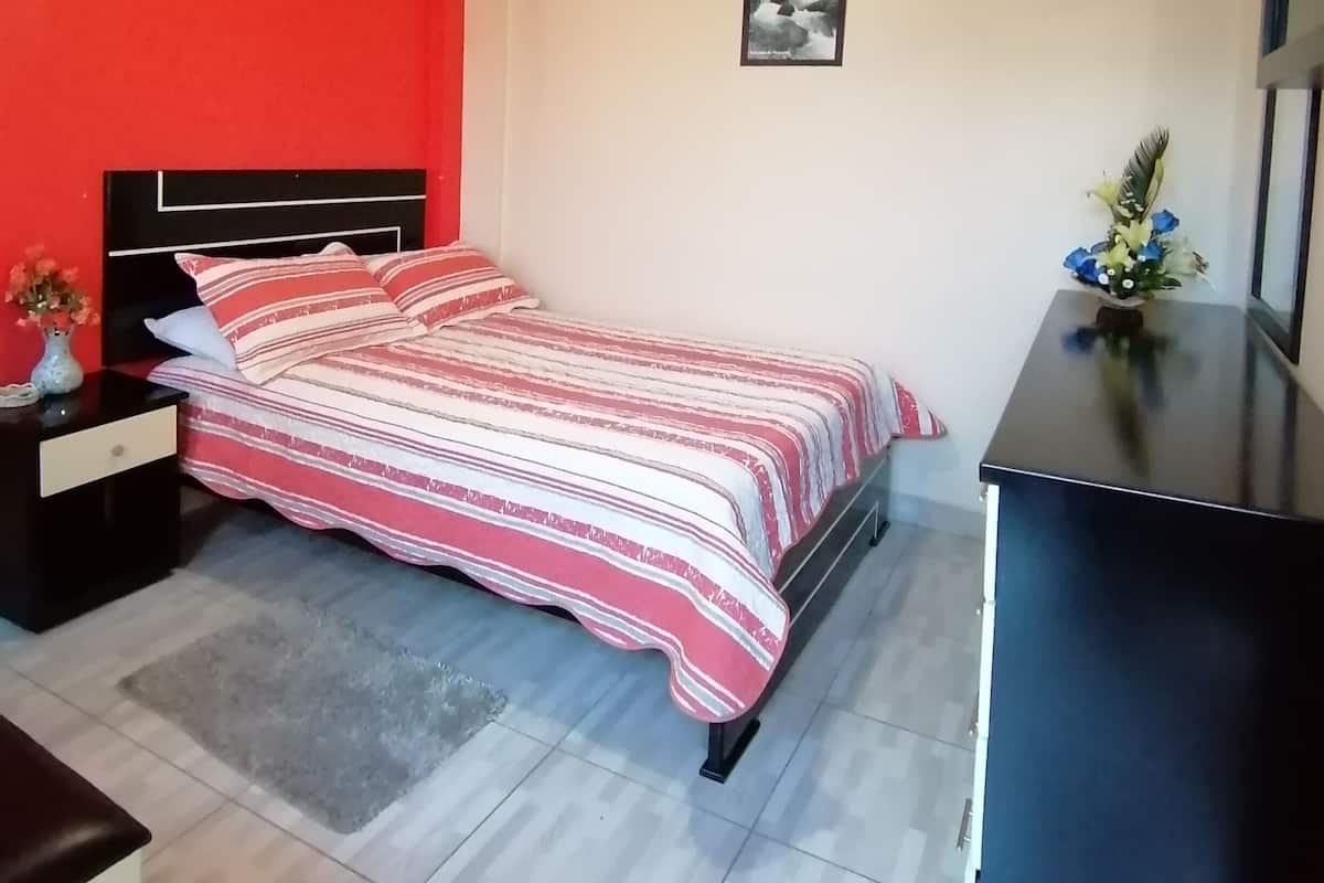 Un dormitorio con una cama, una mesita de noche, un aparador y un cuadro en la pared.