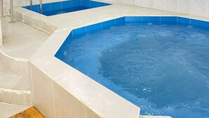A swimming pool with a blue interior, surrounded by white tiled walls and a wooden deck. - Hostal y Complejo recreacional La Playita de Monse (Otavalo)