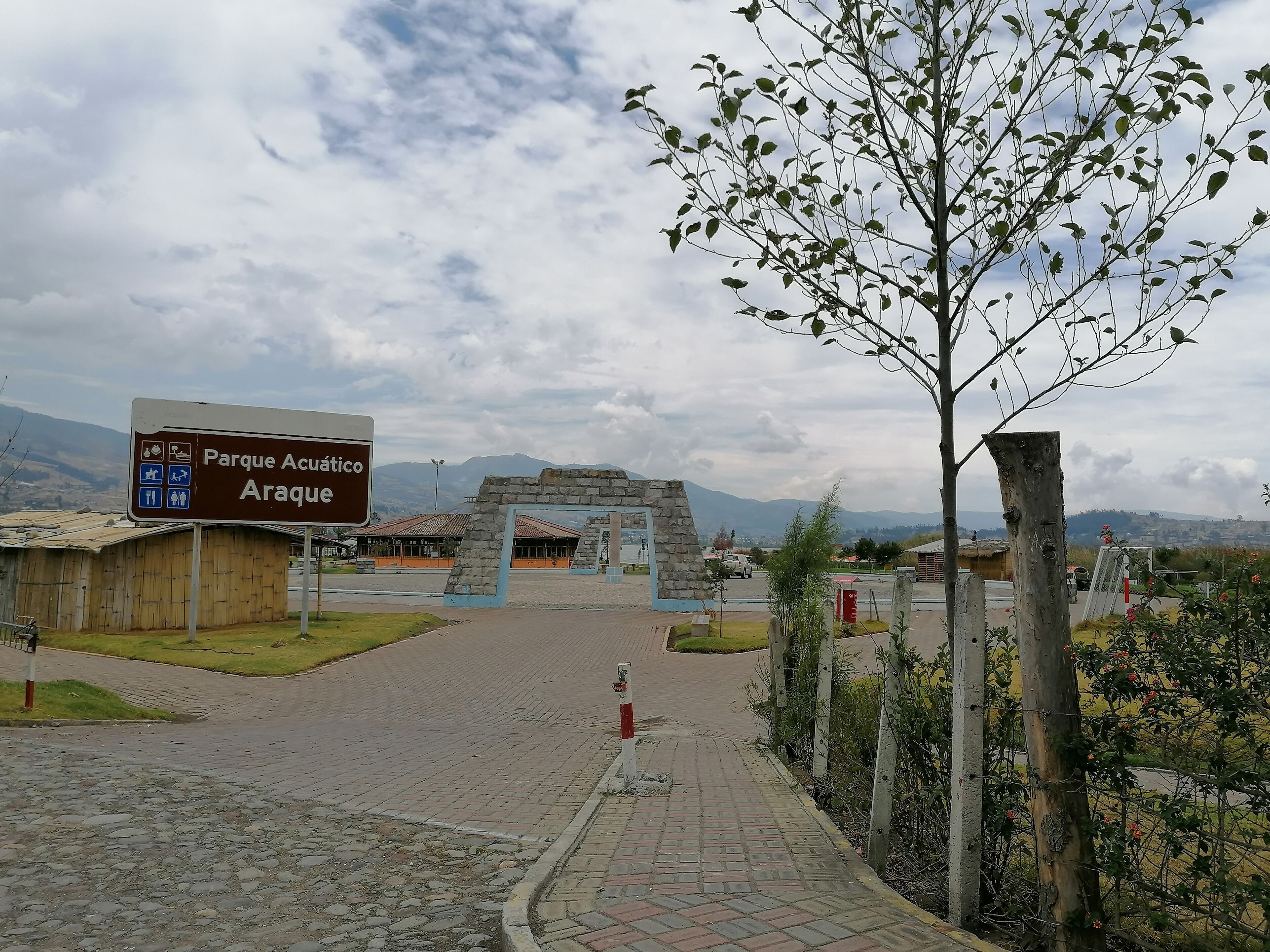 Señal de Parque Acático ARAQUE, con un arco de piedra y un camino pavimentado que conduce hacia él.