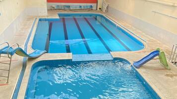 Una piscina interior con varias pistas de natación, un tobogán y un trampolín.