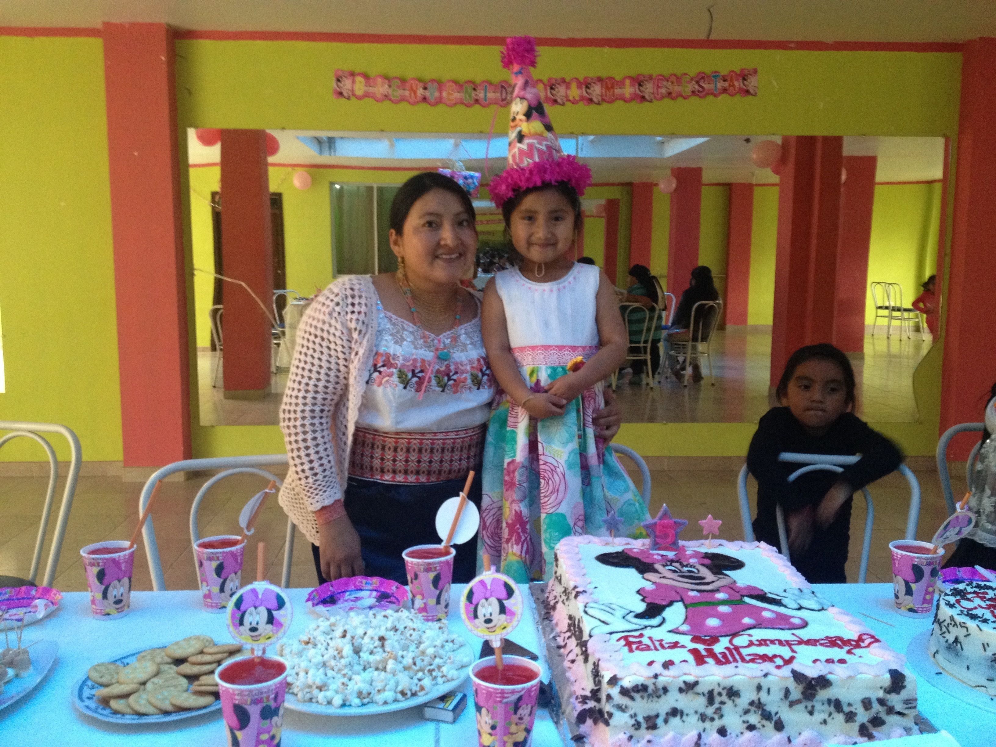 A birthday party with a Minnie Mouse themed cake, snacks, and drinks on a table.