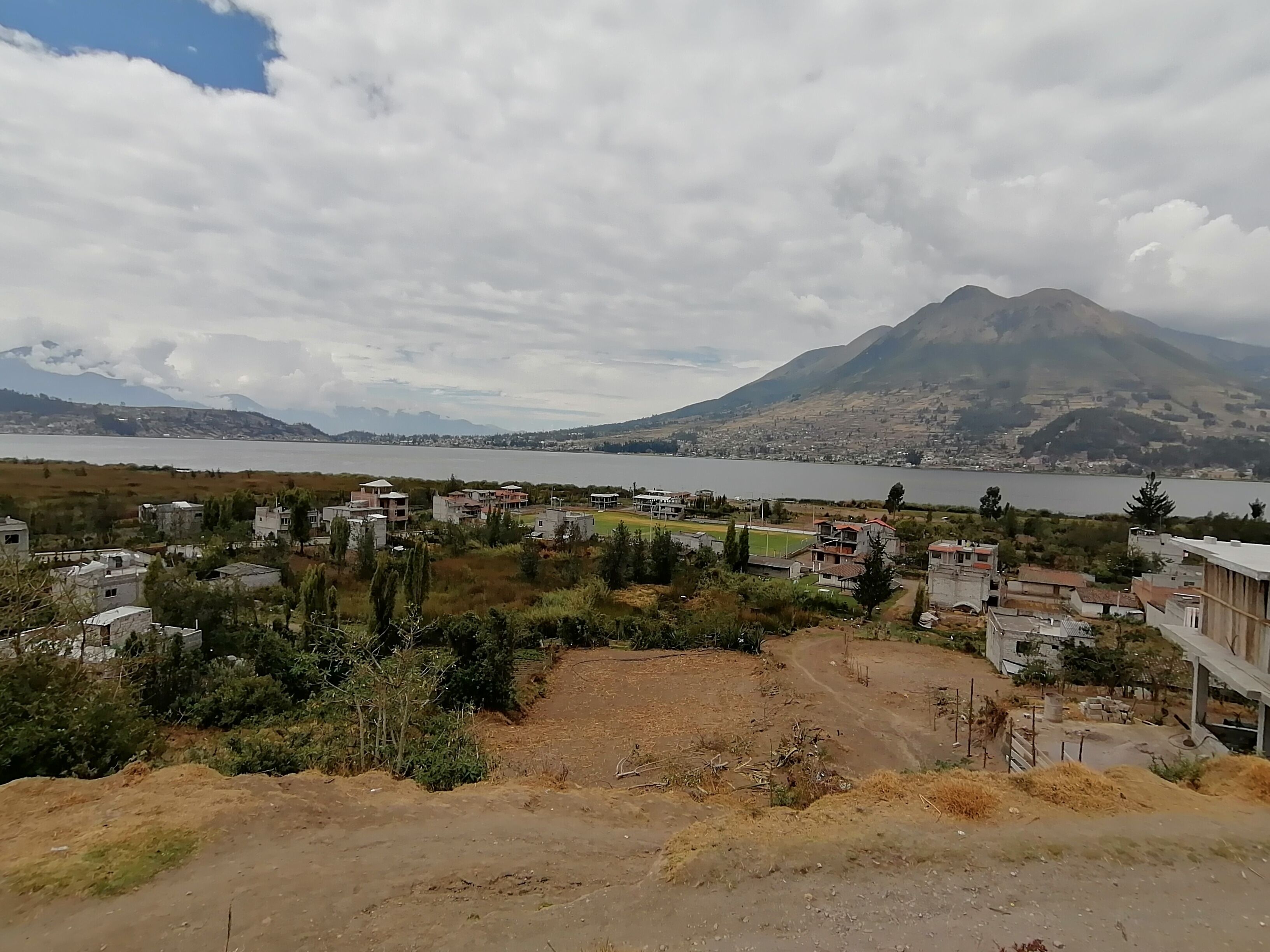 Un pueblo costero con edificios cerca del agua y una montaña al fondo.