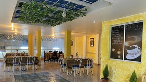 A spacious indoor area with multiple dining tables and chairs, a ceiling with hanging plants, and a large poster on the wall. - Hostal y Complejo recreacional La Playita de Monse (Otavalo)