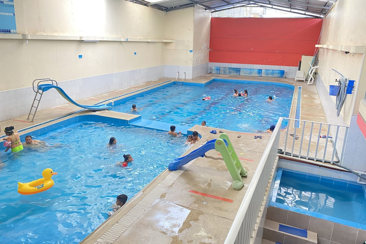 Una piscina interior con varias pistas de natación, un tobogán y una zona de piscina más pequeña separada.