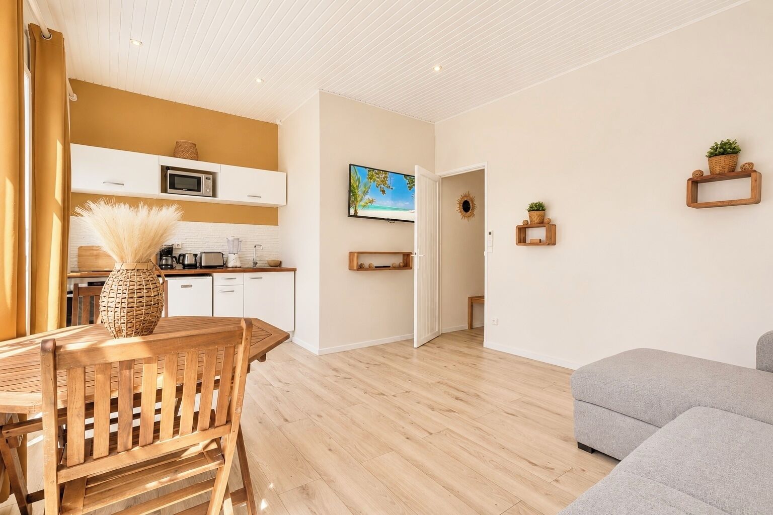 Una cocina moderna con armarios blancos, un microondas y una zona de comedor con mesa y sillas de madera.
