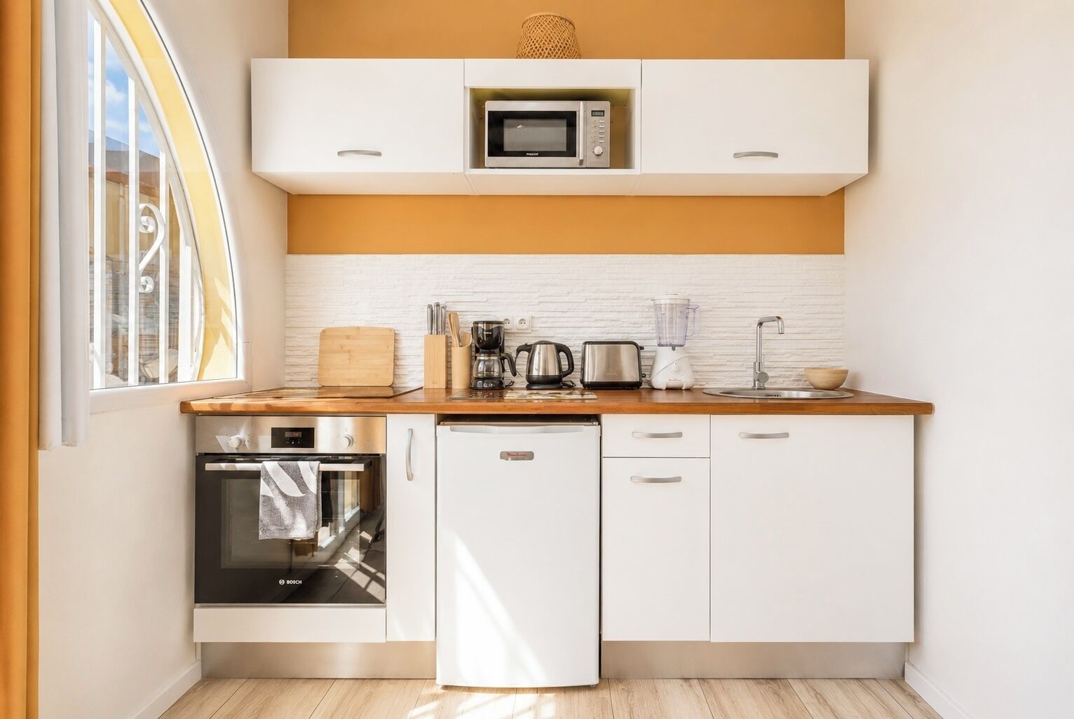 Una cucina compatta dotata di forno a microonde, tostapane, macchina del caffè e lavastoviglie.