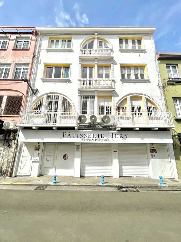 A white building with balconies and a sign reading "Pâtisserie Hery Artisan Pâtissier".