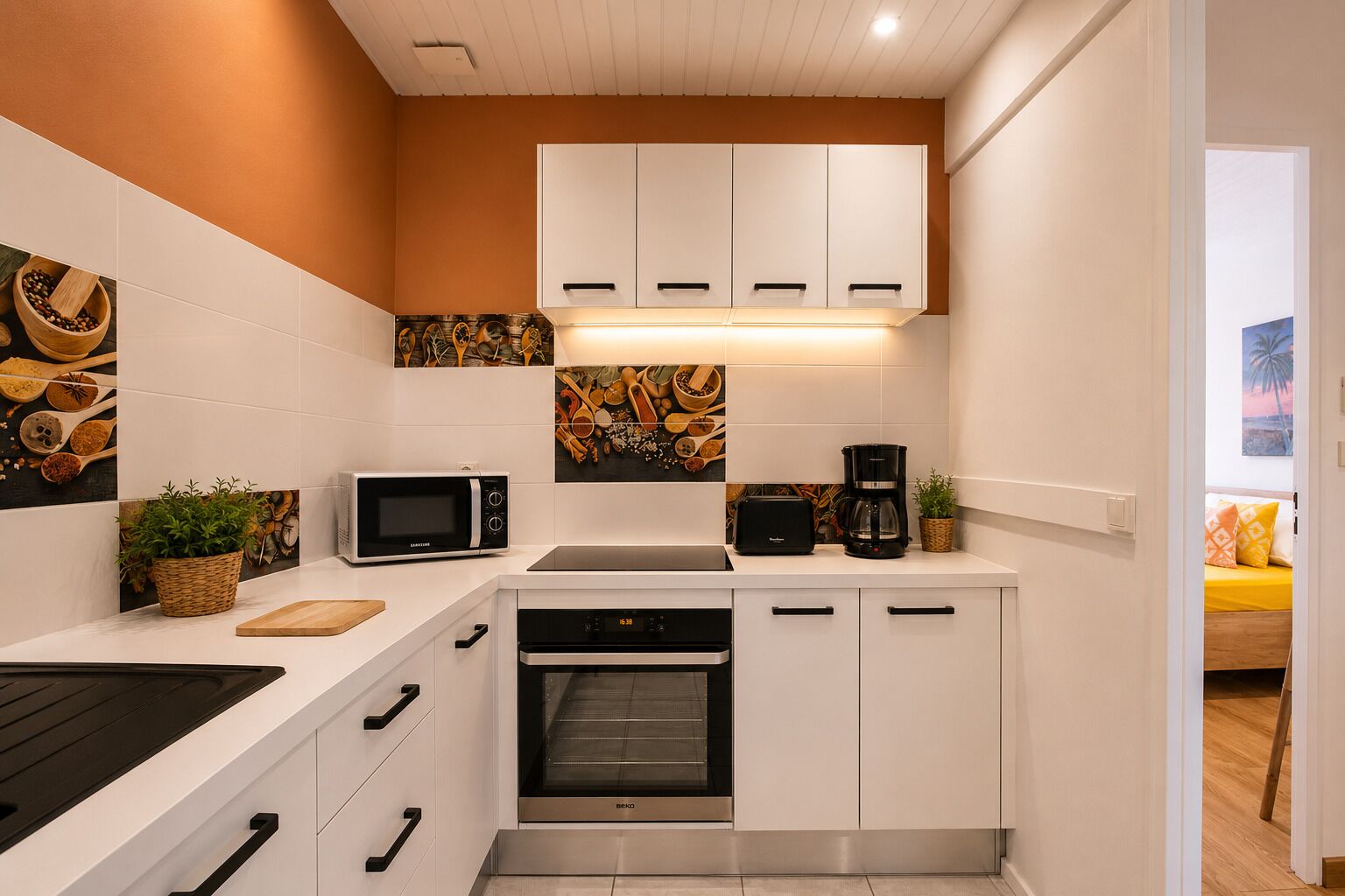 A compact kitchen with white cabinetry, a microwave, a toaster, and a coffee maker.