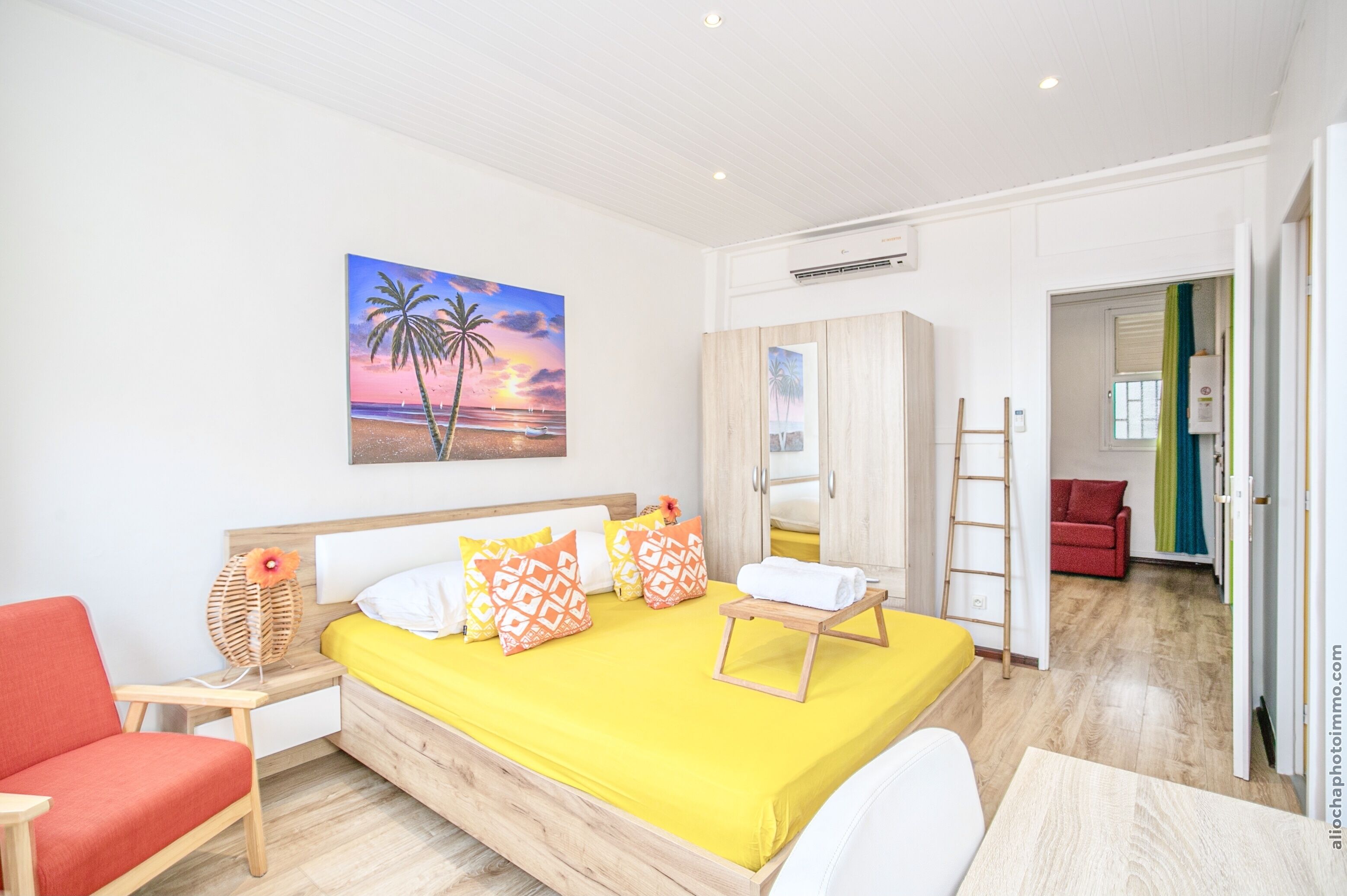 A bedroom with a bed, a nightstand, a chair, a painting, and a wardrobe.