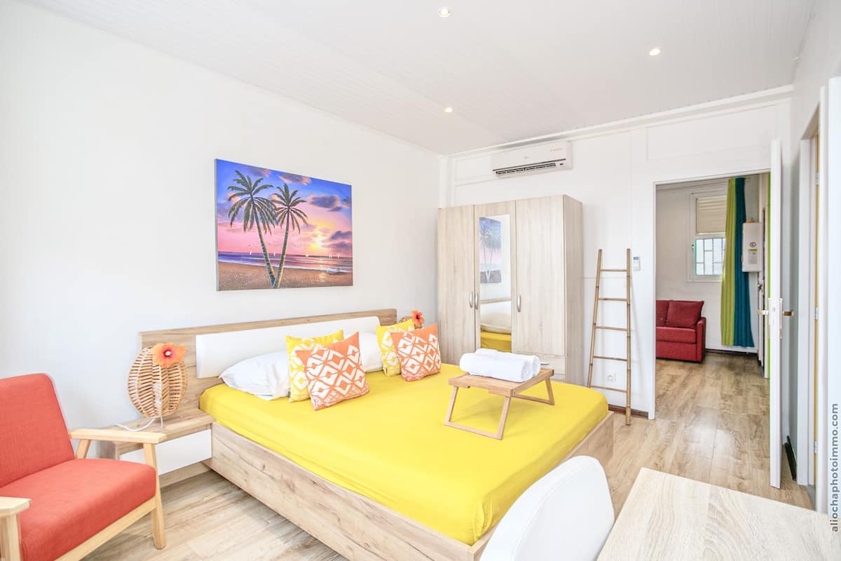 A bedroom with a bed, a nightstand, a chair, a painting, and a wardrobe.