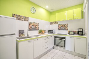 A modern kitchen with white cabinets, a green backsplash, and a microwave. - Foyal Suites (Fort-de-France)