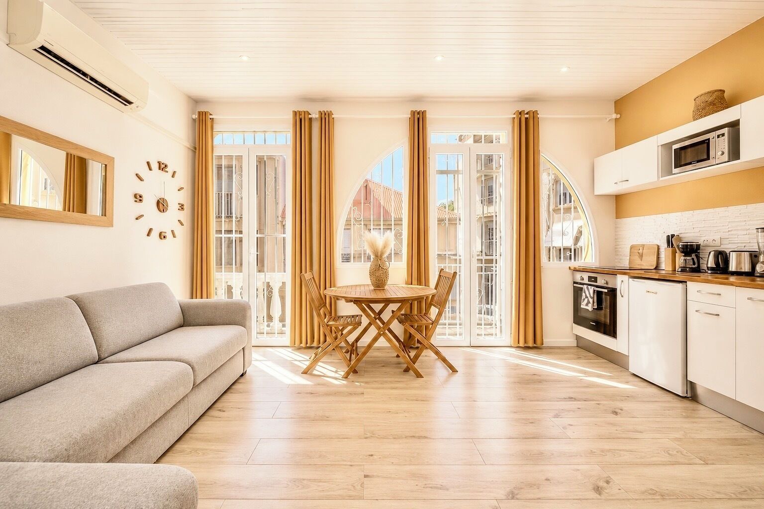 A modern living room with a sofa, a dining table with chairs, and a kitchen area with appliances.