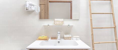 Une salle de bain avec un lavabo blanc, un miroir, un porte-serviettes et une échelle en bois.