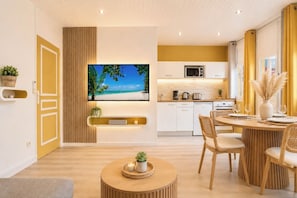 Una cocina moderna con televisor de pantalla plana, armarios de madera y un comedor con mesa y sillas redondas.