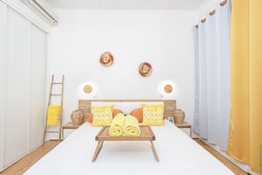 Une chambre d’hôtel avec un lit, une table de chevet, une lampe, un plateau avec des serviettes et une fenêtre avec des rideaux.