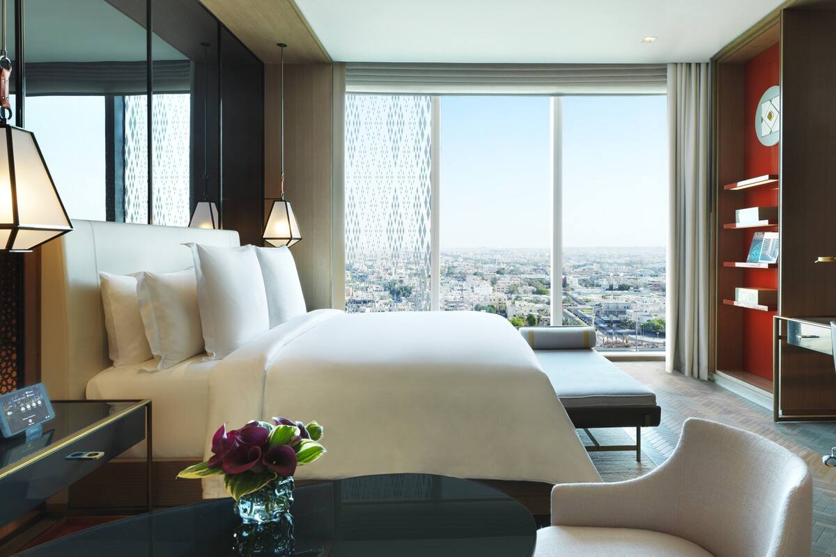 Une chambre d’hôtel moderne dotée d’un grand lit, d’un bureau, d’une chaise, d’une télévision et offrant une vue sur la ville.