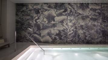 Ein modernes Badezimmer mit Marmorwand, einer Badewanne und einer Sitzbank.