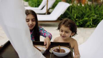 Dos niños sentados a una mesa con tazones de comida, probablemente disfrutando de una comida al aire libre.