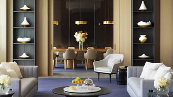 A modern hotel lobby with a dining area, sofas, and a coffee table with fruit and a vase.