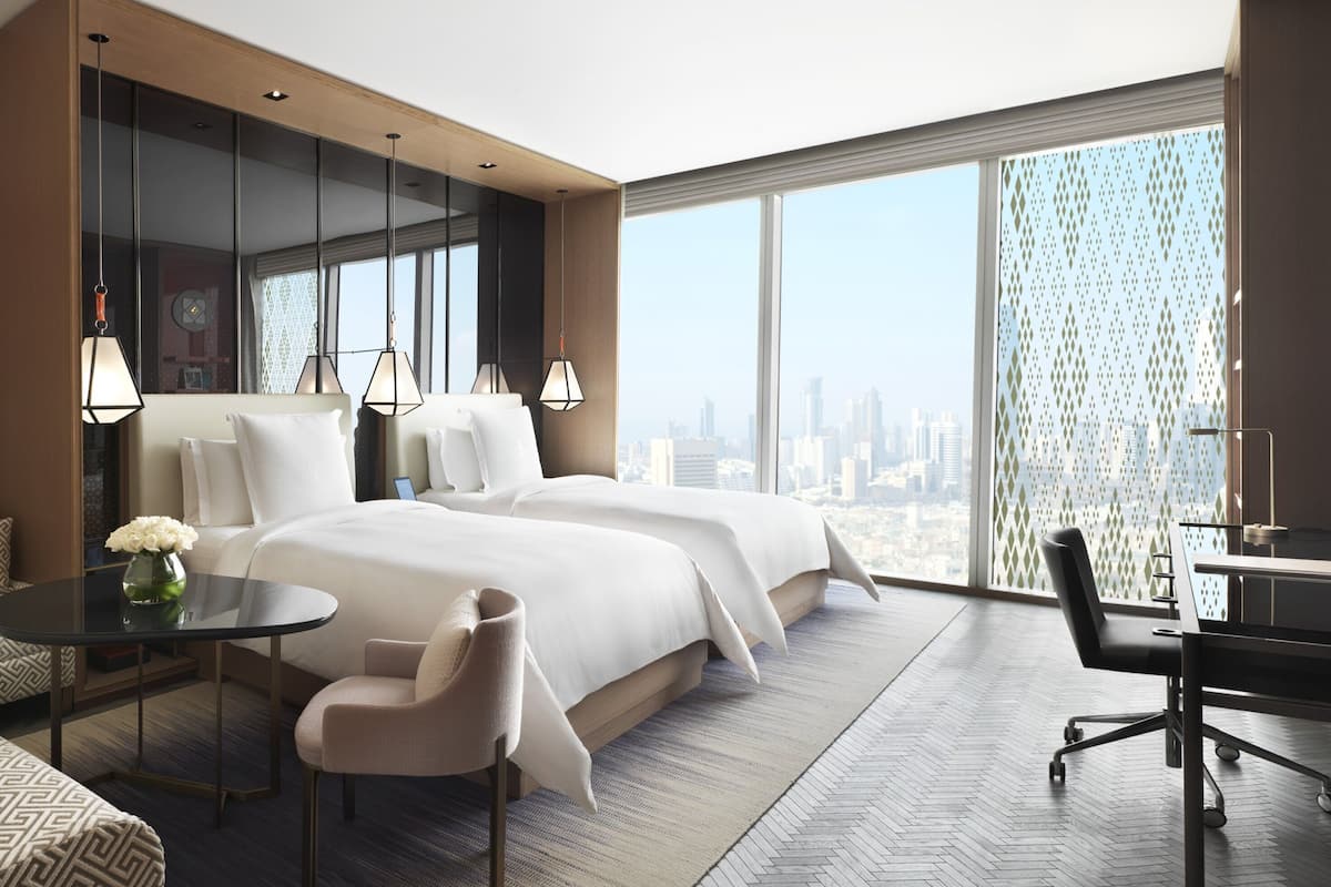 Une chambre d’hôtel moderne dotée d’un grand lit, d’un canapé, d’un bureau et offrant une vue sur la ville.