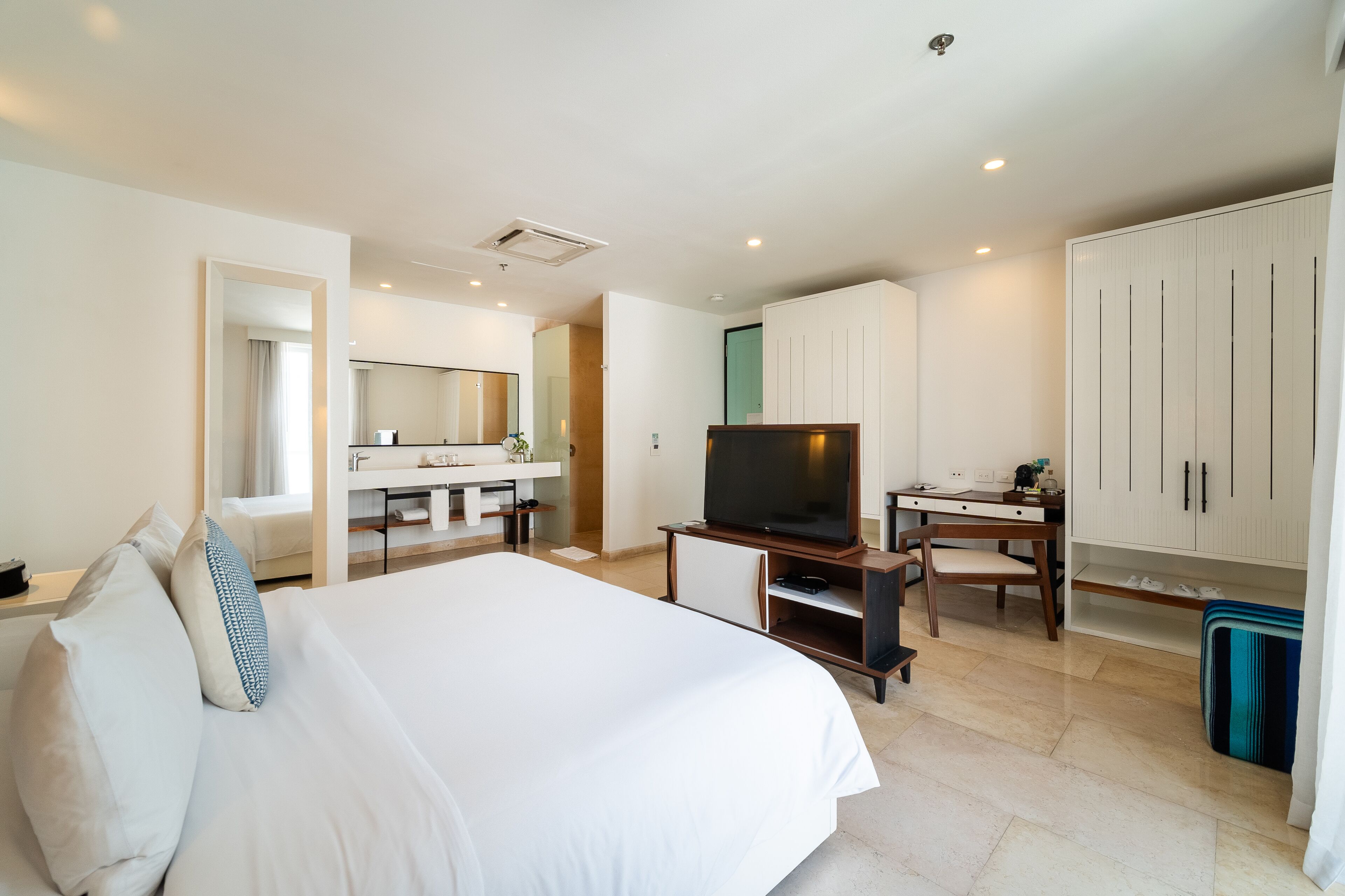 Ein Hotelzimmer mit einem großen Bett, einem Fernseher, einem Schreibtisch und einem Kleiderschrank.