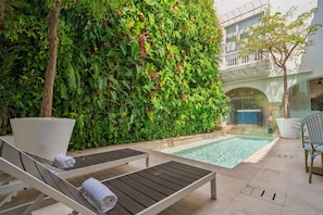 A poolside area with a wall of dense foliage, a lounge chair, and a small pool. - Nacar Hotel Cartagena, Curio Collection by Hilton (Cartagena)