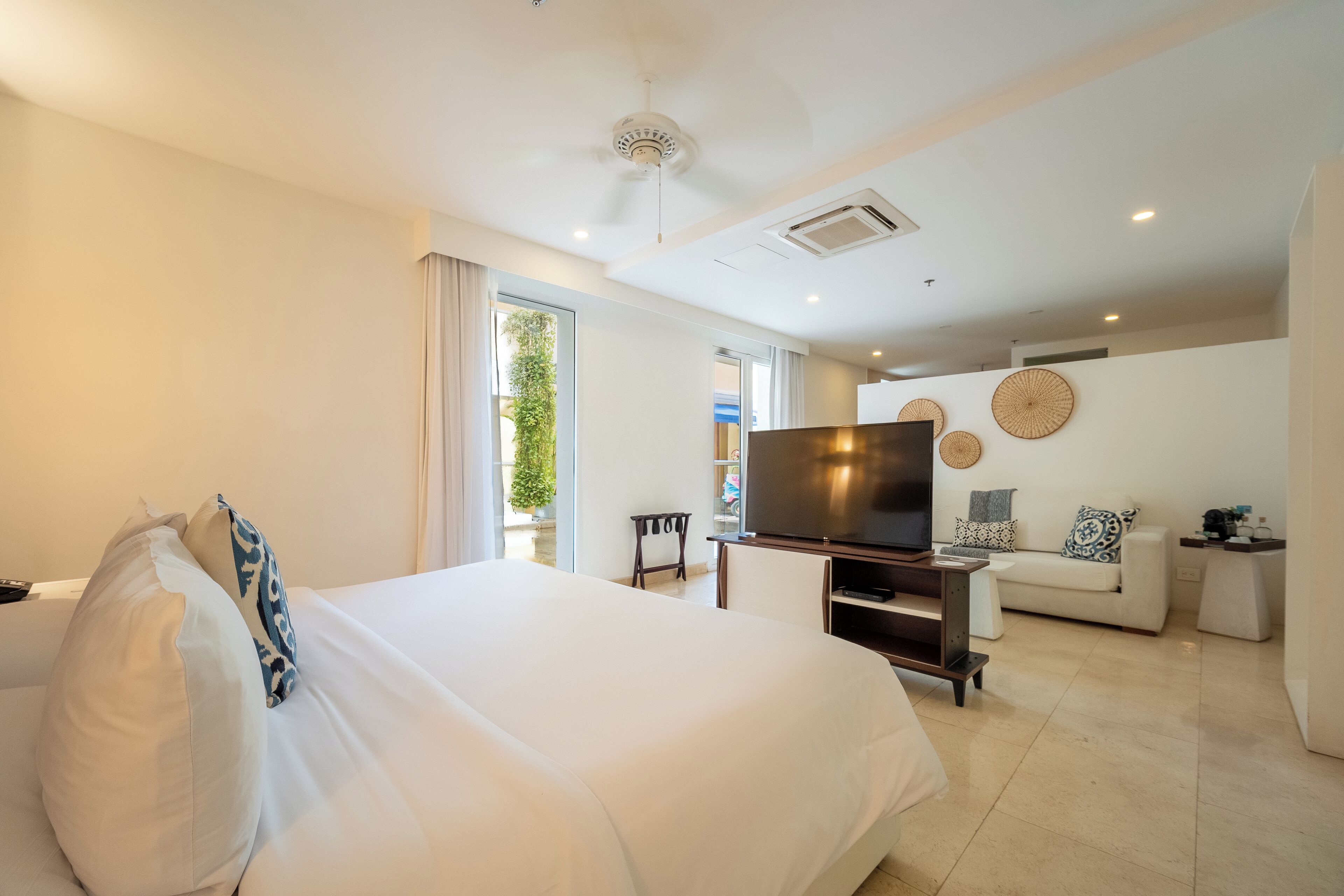 A hotel room with a large bed, a TV, a sofa, and a dining area.