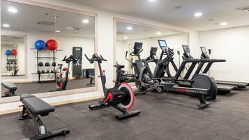 A gym with exercise equipment, a bench, and a mirrored wall.