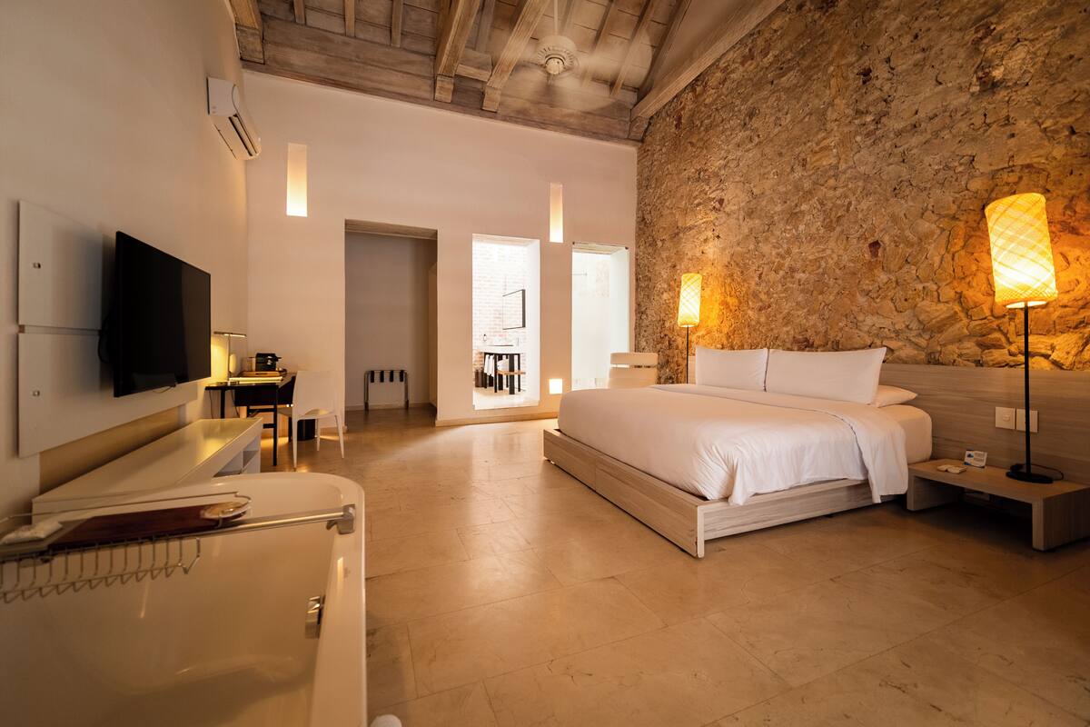 Un dormitorio moderno con una cama grande, un televisor de pantalla plana en la pared y una pared de acento de piedra.