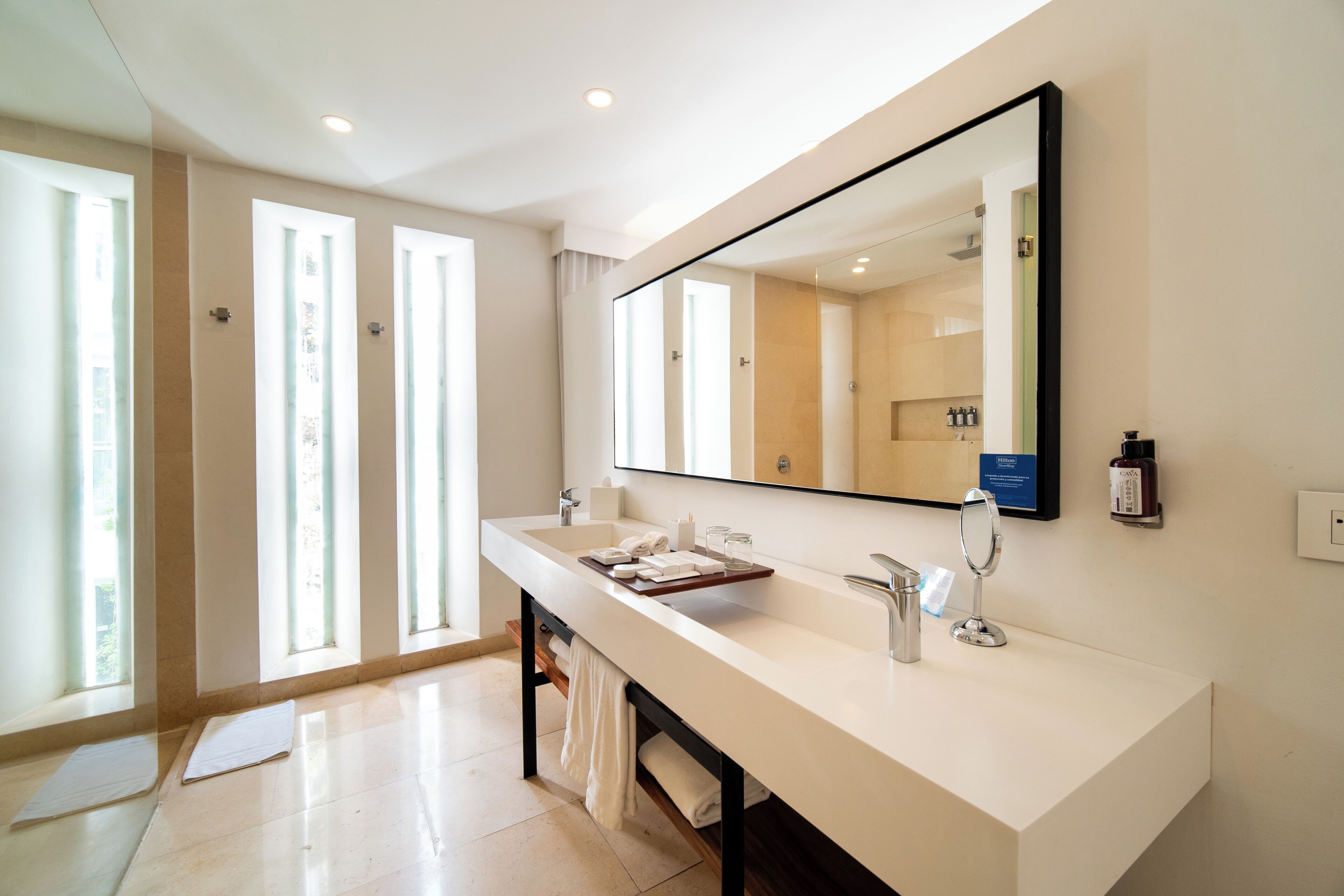 A modern bathroom with a large mirror, a white sink, and a towel rack.