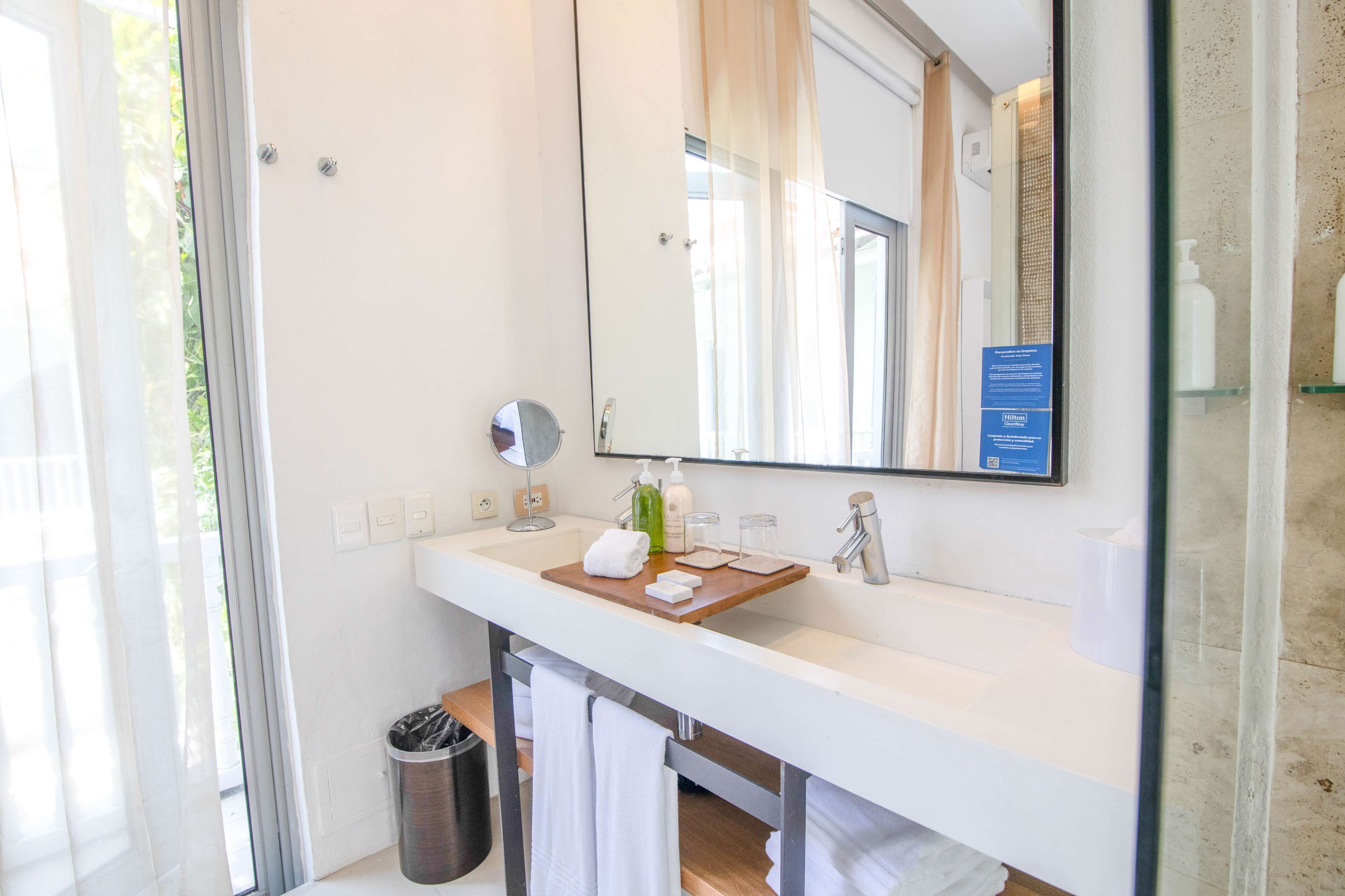 A modern bathroom with a large mirror, white countertop, and a glass shower enclosure.