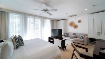 A modern hotel room with a large bed, a sofa, a TV, and a desk.