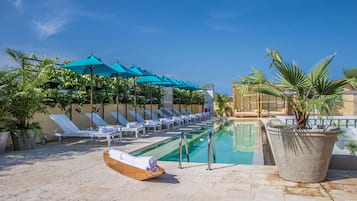 Relax by the serene pool surrounded by lush greenery and comfortable sun loungers.