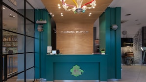 Un mostrador de recepción con una decoración azul aguamarina, techo de madera y un cartel que indica la zona de recepción.