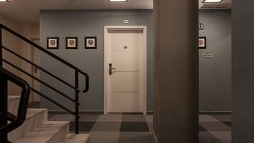A hotel lobby with a checkered floor, a white door, and framed pictures on the wall.