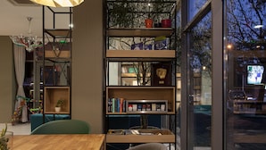 Un interior moderno con una mesa de madera, sillas, una estantería y un ventanal grande.