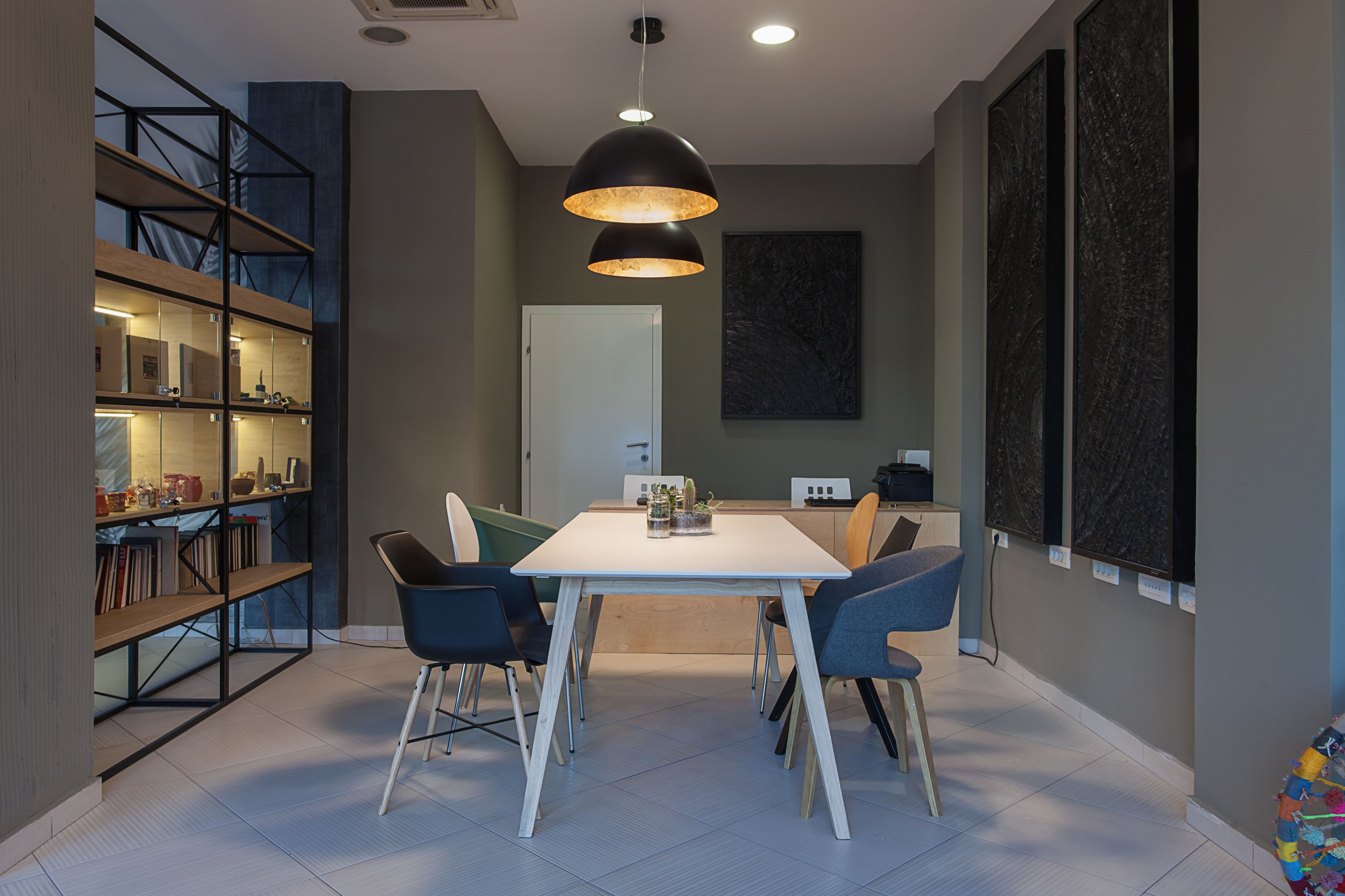 A modern dining area with a white table, black chairs, and a pendant light.