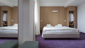 Ein modernes Hotelzimmer mit einem großen Bett, einer Bank und einem Kleiderschrank mit Kleidung.