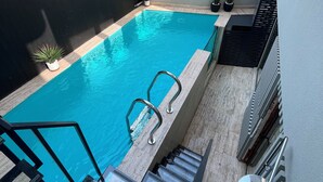 Una pequeña piscina exterior con una escalera metálica y escalones que bajan al agua.