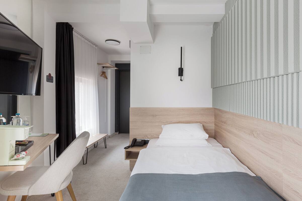 Ein modernes Hotelzimmer mit Bett, Schreibtisch, Stuhl und Fernseher.