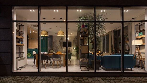 Un interior moderno con comedor, sofás y una escalera que lleva a un nivel superior.