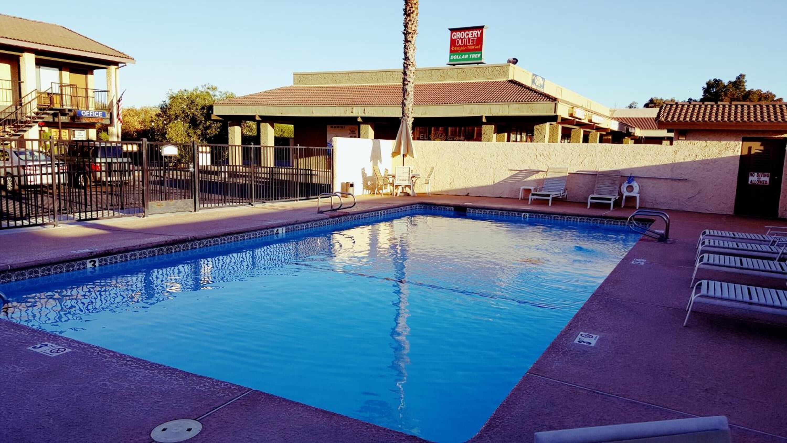 A swimming pool with lounge chairs and a fenced area.